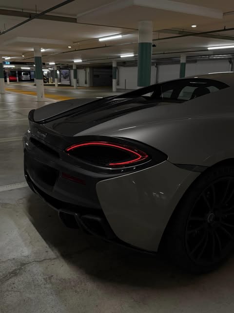 Heckpartie des McLaren 570S in einer Tiefgarage, ovale Rückleuchte mit rotem Leuchtring und Heckdiffusor