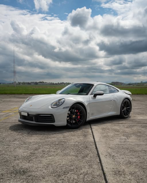 Porsche 911 Carrera 4S in Kreideweiss auf freiem Feld unter bewölktem Himmel