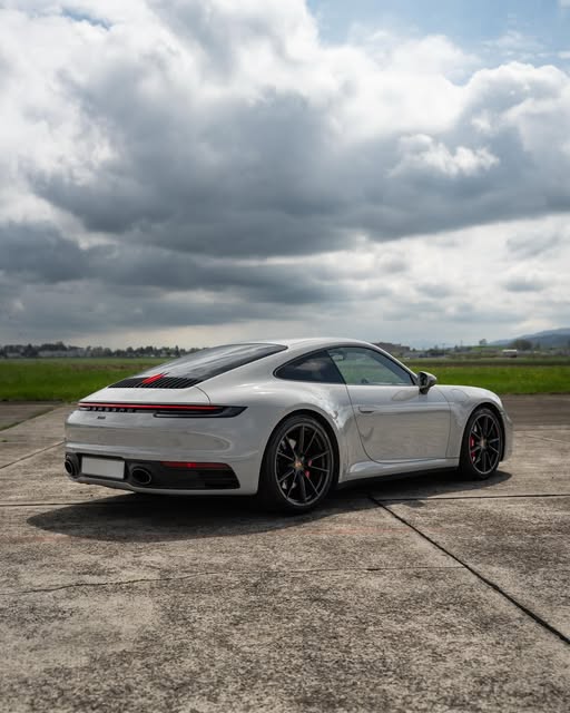 Porsche 911 Carrera 4S in Kreideweiss, Heckansicht von schräg hinten unter bewölktem Himmel